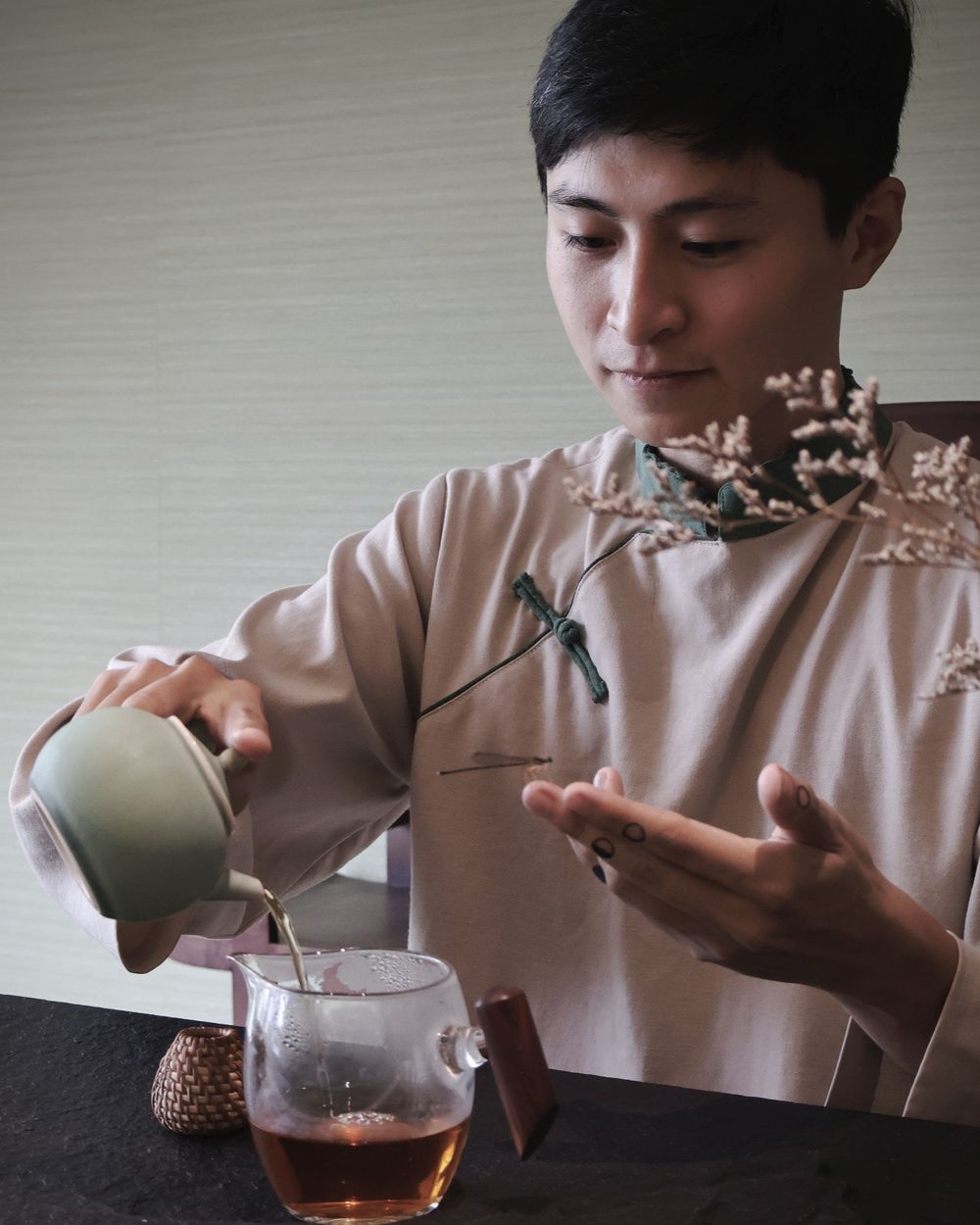 Trà Vũ rót trà bên một cành hoa